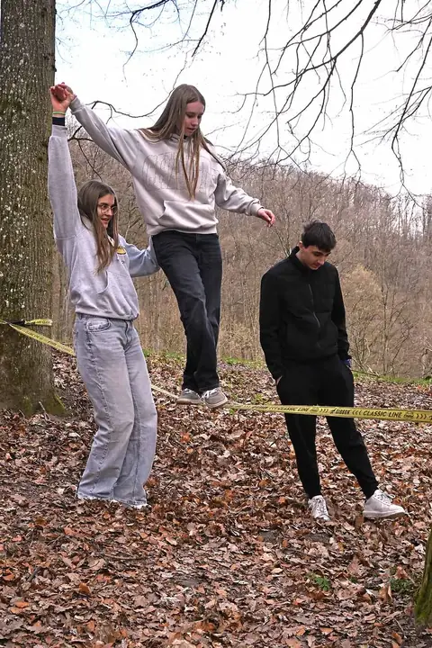 Lehrlinge balancieren auf einer Slackline im Wald